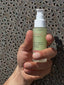Hand holding a bottle of energin C serum against a textured metal background