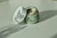 Green jar of detox mask  with a white lid on a light surface