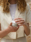 Tara holding a jar of earth cream against a neutral background