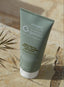 Tube of emerginC Scientific Organics body butter on a stone surface with a leaf
