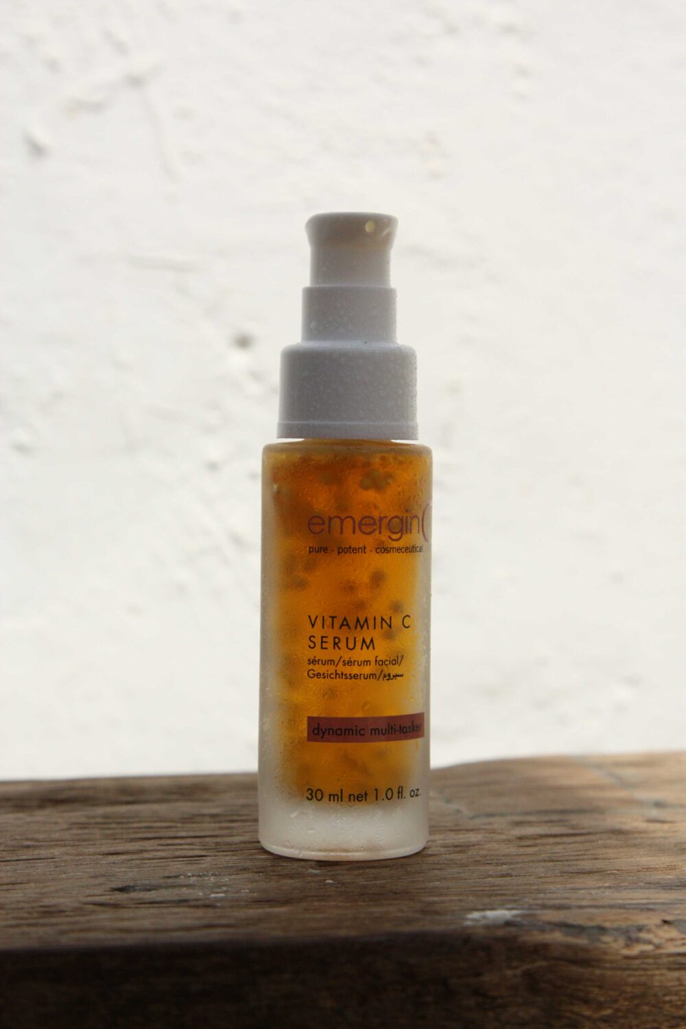 The emerginC vitamin C serum photographed in daylight with white wall in the background